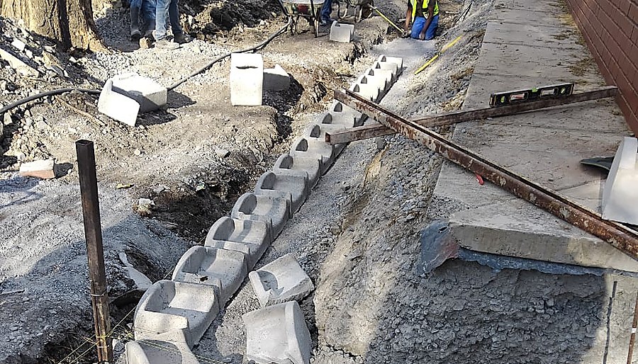 Workers installing precast concrete retaining wall units with a spirit level checking alignment