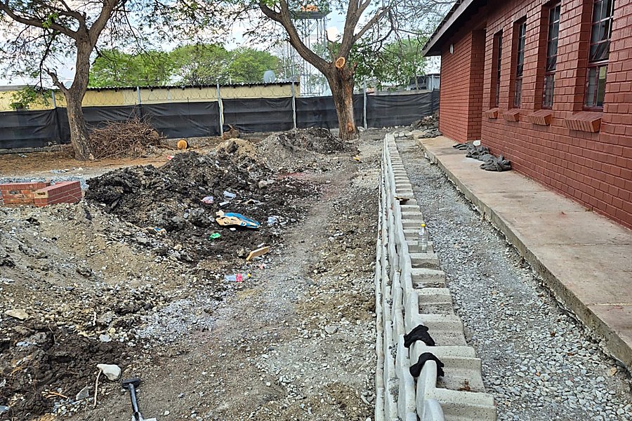 Newly installed precast concrete retaining wall units along a brick building