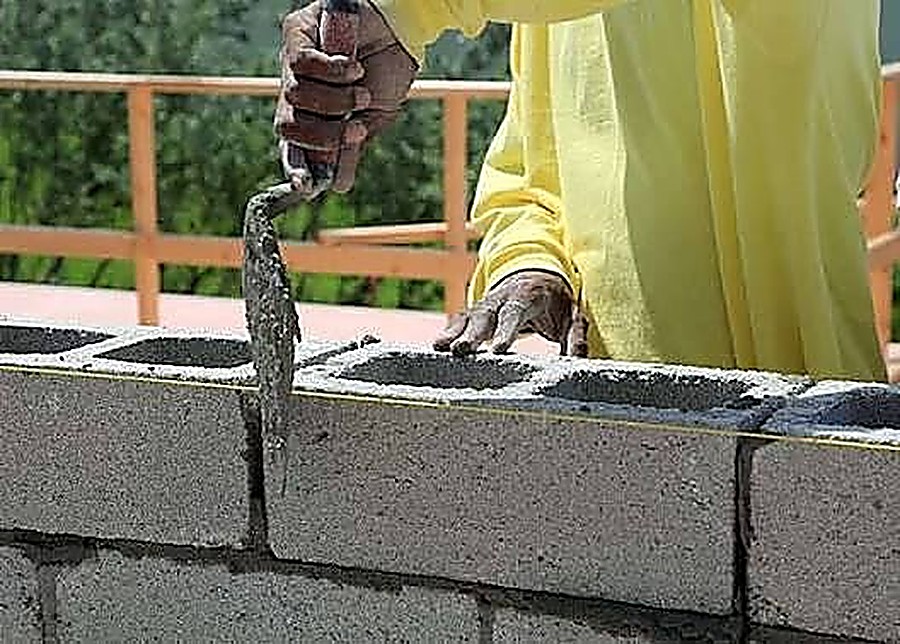 Bricklayer applying mortar to a concrete block wall