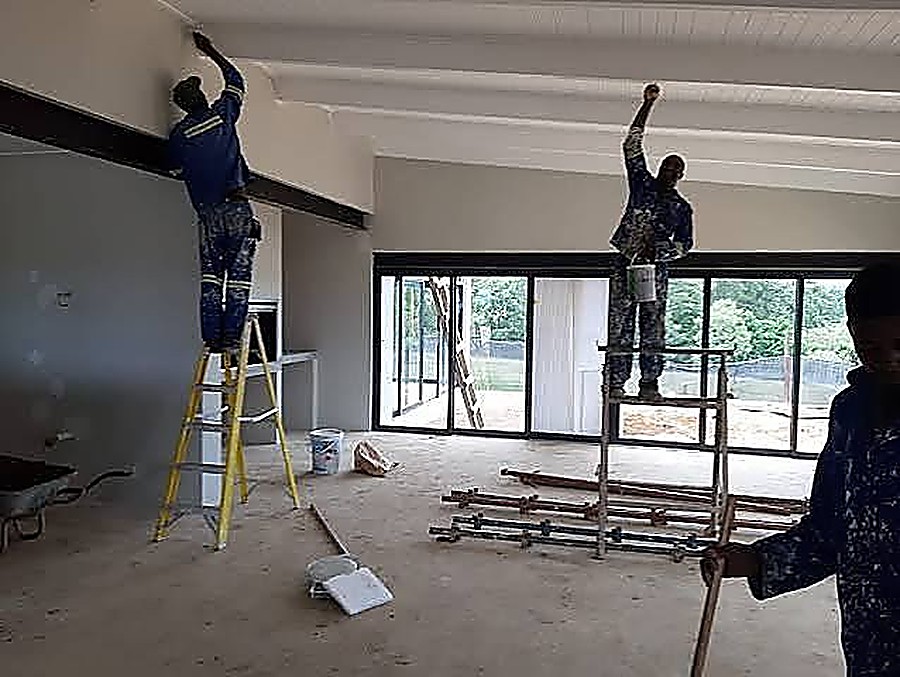 Workers finishing and painting a vaulted wood ceiling interior