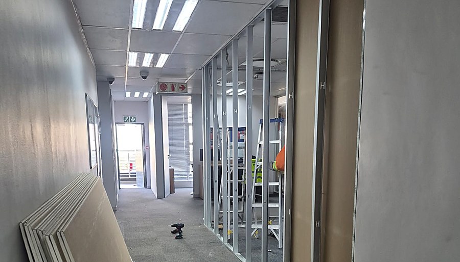 Aluminium partition framing and drywall boards ready for installation in an office corridor