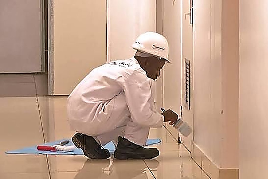 Painter applying detail coating to a wall corner indoors