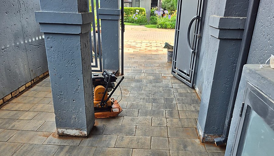 Plate compactor on freshly laid paving at a covered walkway entrance