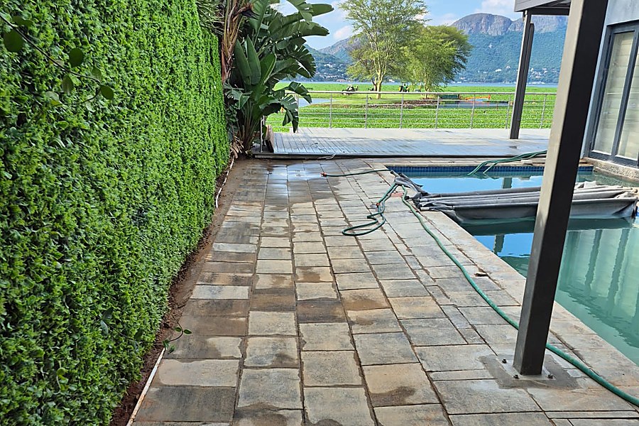 Finished paved poolside patio and pathway with garden hedge, lake and mountain view