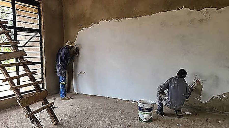 Plasterers applying and floating a skim coat inside a new room