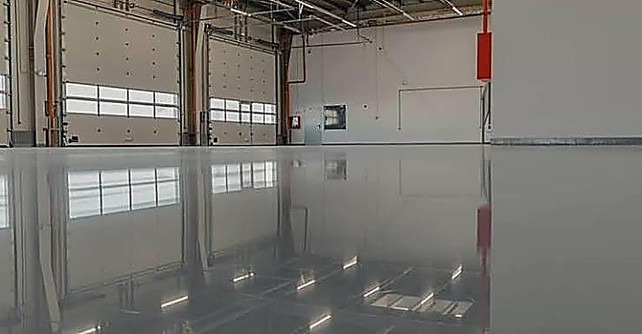 Polished epoxy flooring inside a commercial warehouse with roller doors